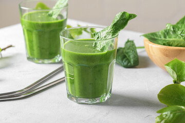 Healthy green smoothie with spinach, avocado, banana, and vegan milk in two glasses and fresh ingredients on light table