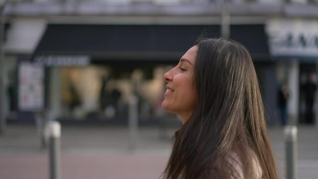 Profile closeup face of a happy young woman walking in city street turning head to camera smiling