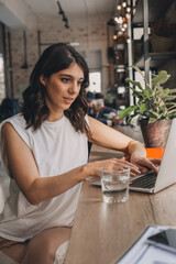 Attractive positive young woman using a laptop in a cafe.Remote work,blogging,business, freelance,e-learning.
