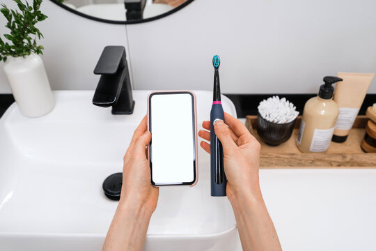 woman brushing teeth with modern dental device at home