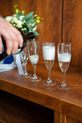 A man's hand pours champagne from a bottle into glasses. 