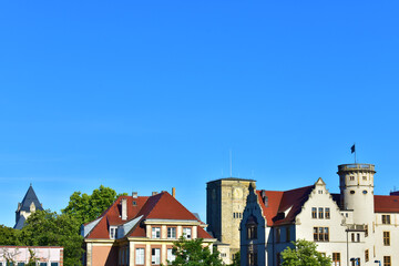 Old buildings with beige walls and red roofs on the horizon, and a wide background of blue cloudless sky. Ancient architecture. Cityscape view. Sunny summer day. Poland, Poznan, July 2022.