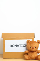 Kid Donation, Charity, Volunteer, Giving and Delivery Concept. Bear doll and Clothes with Donation box at home for support and help poor, refugee and homeless people. Copy space for text