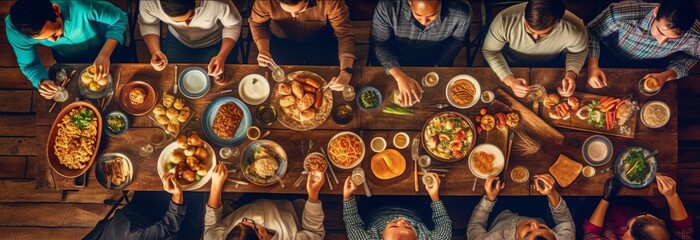 Fototapeta premium a group of people sitting at a large dinner table with plates of food on them, in the style of rustic texture, spontaneous gesture, high-angle, photo taken with provia