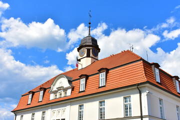 Old architectural building with white walls and red roof. Tower with a spire and an old clock at the top. Sunny summer day with blue sky. Kurnik, Poznan, Poland, June 2022. © B.inna