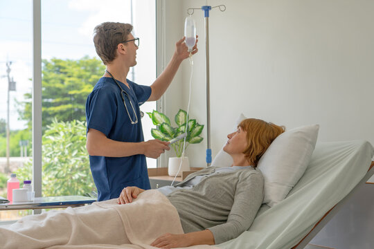 A doctor is explaining treatment guidelines to a female patient lying in IV fluid in a hospital.
