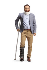 Full length portrait of a man with a neck collar and orthopedic boot standing with a crutch
