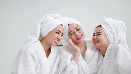 Beautiful young asian women in bathrobes and towels on heads with collagen patch on under eyes smiling with bestfriens. Self care and daily beauty routine