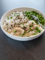 Chicken fricassee or ragout with basmati rice and wild rice. Served with  green peas on a plate isolated on a table