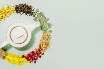Organic herbal tea. Concept of healing herbal tea, healthy drink and home herbal apothecary. Dry wild growing flowers and herbs with teapot on blue background. Flat lay, copy space