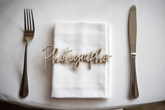 Photographer wedding table place wooden text name card place marker.  Joined up text showing place for wedding breakfast food meal.