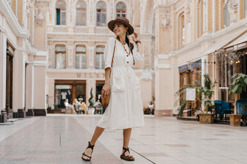 Naklejka premium attractive woman walking in shopping street in Italy on vacation dressed in white summer fashion dress