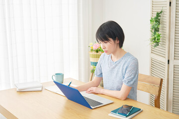 リビングでノートパソコンを使って勉強する女性