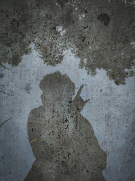 A shadow of a person in a puddle