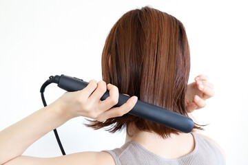 Fototapeta premium ストレートアイロンを使う女性 ヘアセット