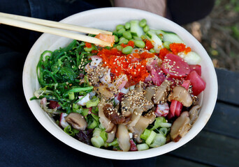 poke bowl colorful detail with cucumber, octopus, masago, tobiko, sesame seeds, pickled radish, seaweed salad, edamame, soy beans, marinated shitake mushrooms, scallions, ponzu sauce, salmon)