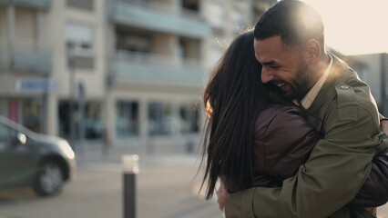 Happy genuine reunion_ Two people embracing in street feeling ecstatic. Authentic hug standing outdoors in urban environment