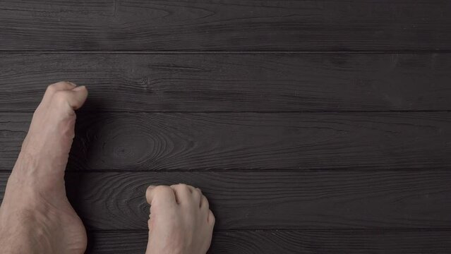 Male feet with extremely long and terribly untrimmed nails on a black wooden background or floor. Close up, top view, point of view. Copy space for advertising text