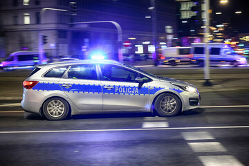 Fototapeta na wymiar Alarmowo Radiowóz polska policja z Sygnalizator błyskowy niebieski na dachu radiowozu. Nocna interwencja. 