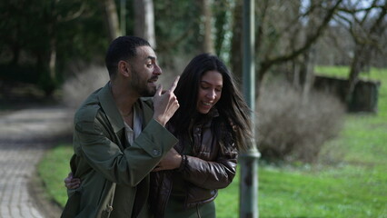 Happy Arab couple laughing and smiling walking together in outdoor park during sunny beautiful day. Tracking shot of a joyous man and woman in conversation