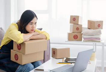 Asian woman think hard serious working laptop computer at home selling online start up small...