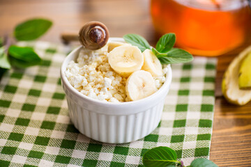 crumbly organic cottage cheese with honey and bananas in a ceramic bowl