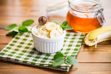 crumbly organic cottage cheese with honey and bananas in a ceramic bowl