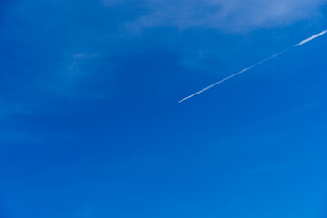 Jet plane contrail in blue sky without clouds, minimalistic natural sky background, a plane is flying high in the sky, cruise missile strikes, azure sky. Copy space