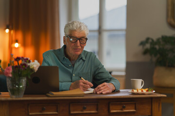 Senior man writing notes in his diary.