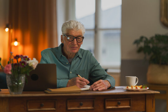 Senior man writing notes in his diary. - Powered by Adobe