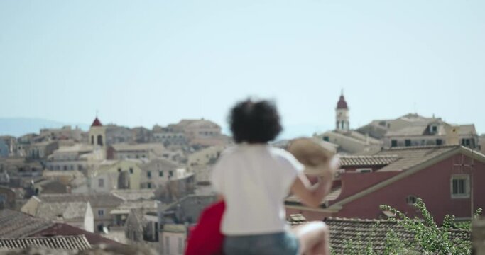 Woman enjoy aerial panoramic view of Kerkyra, capital of Corfu island, Greece from new venetian fortress, slow motion. Female tourist wear hat, white shirt and red backpack