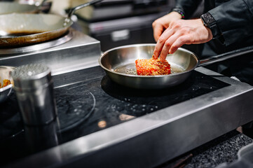 man chef cooking fried tuna fish in frying pan on kitchen