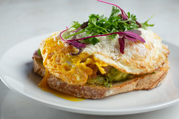 A view of a plate of avocado toast, featuring a fried egg.