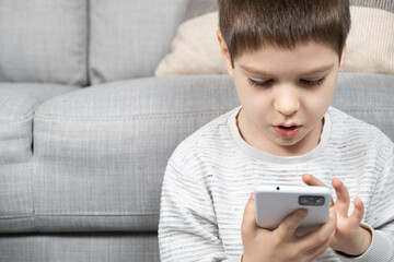 A preschool boy uses a smartphone, plays games on his phone, place for text