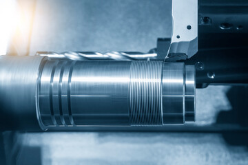 The  CNC lathe machine forming  cutting the metal shaft parts in the light blue scene.