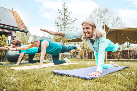 Sporty senior women doing exercise in garden during group training - Mature female exercising  hands and knees balance outside - Healthy life style concept