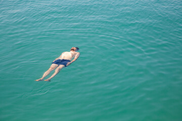 A man floating in the sea, top view.