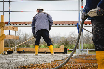 Beton gießen auf der Baustelle mit gelben Stiefeln