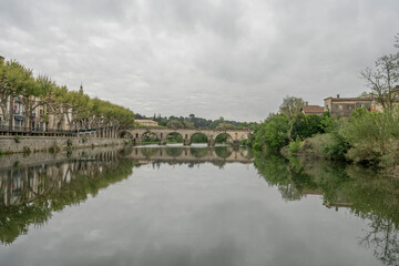Obraz premium Sommieres, France - 04 22 2023: View of the Sommieres Roman bridge reflecting in the Vidourle river