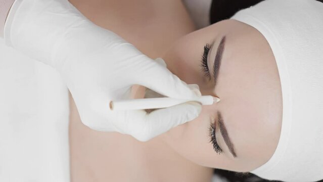 The beautician makes markings on the face for injection of Botox close up. Professional skin care, painless rejuvenation procedure in a beauty salon. Butolin toxin and other fillers to smooth wrinkles