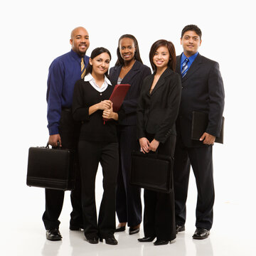 Multi-ethnic business group of men and women standing with briefcases looking at viewer.