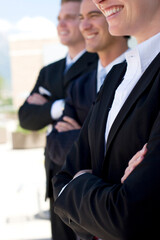 Fototapeta na wymiar one female two males wearing business suits standing in a row smiling