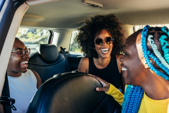Joyful diverse friends in car having fun during holidays