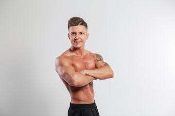 Fototapeta na wymiar Muscular young healthy fit guy with a hairstyle with a muscular body stands hand in hand on a white background in the studio