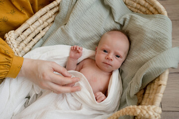 Crop mother adjusting swaddle on newborn baby