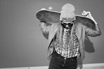 A young hipster girl is riding a skateboard. Girls girlfriends for a walk in the city with a skateboard. Spring sports on the street with a skateboard. © alexkich