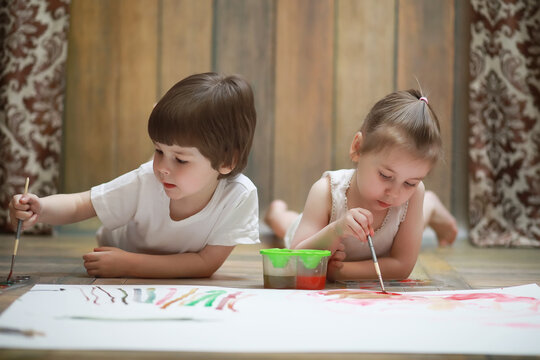 Little children paint on a large sheet of paper