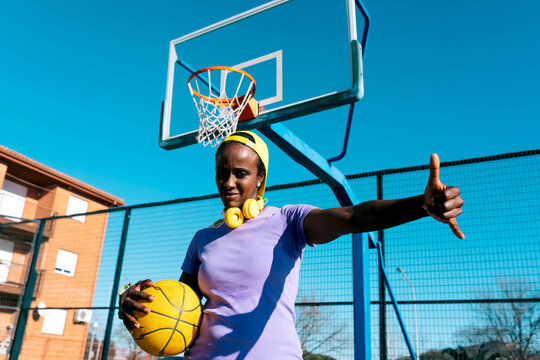 Black female basketball player showing shaka sign on outdoor sports ground
