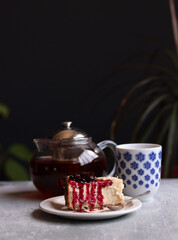 A piece of cherry cheesecake on a white plate and a teapot. Close up photo of homemade dessert. Sweet food concept. 