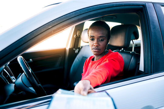 Sad young woman on driver seat showing documents